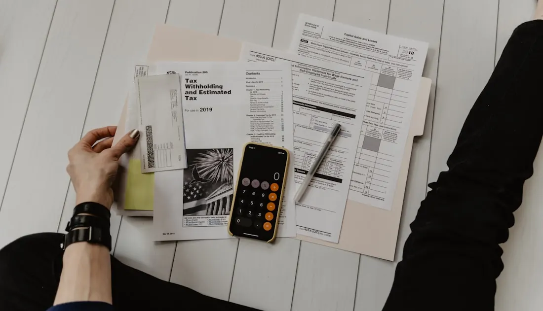A desk with a laptop, notebook and calculator used for project budgeting
