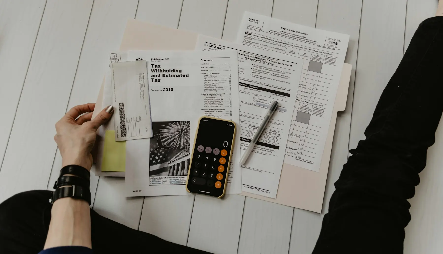 A desk with a laptop, notebook and calculator used for project budgeting